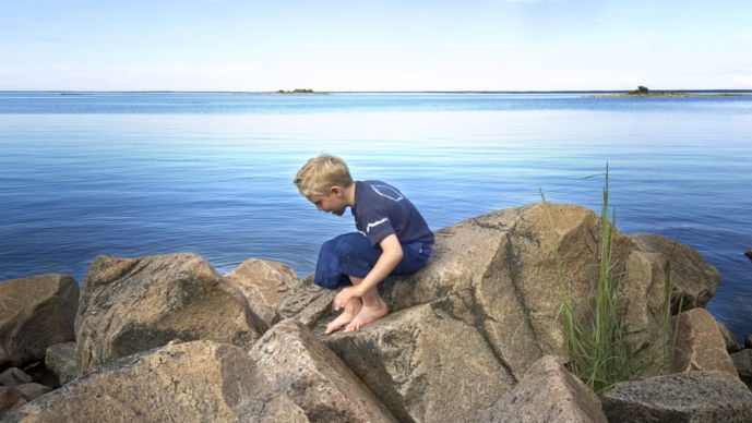 Pojke klättrar vid havets horisont